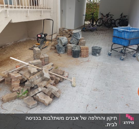 ערימת לבנים, דליים וכלי עבודה בחצר